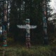 a group of totem standing in a forest - photo by galen crout