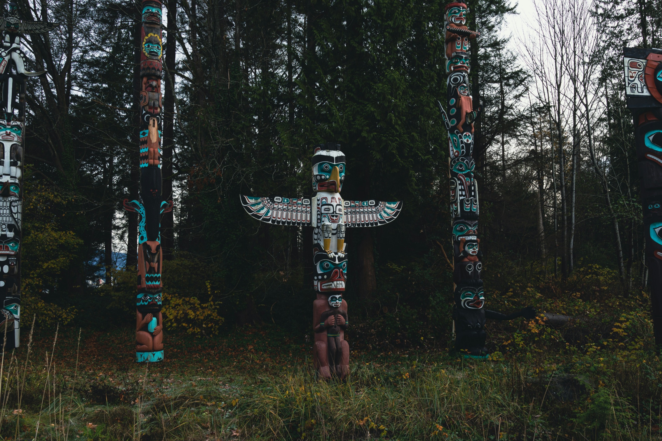 a group of totem standing in a forest - photo by galen crout
