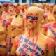 Dozens of mannequins wrapped in orange tape with protest messages such as "Justice," "#MeToo," and "Do not look away" displayed prominently. The installation highlights issues such as violence, stalking, and harassment, with bold text and symbols creating a powerful visual statement. Photo by Mika Baumeister