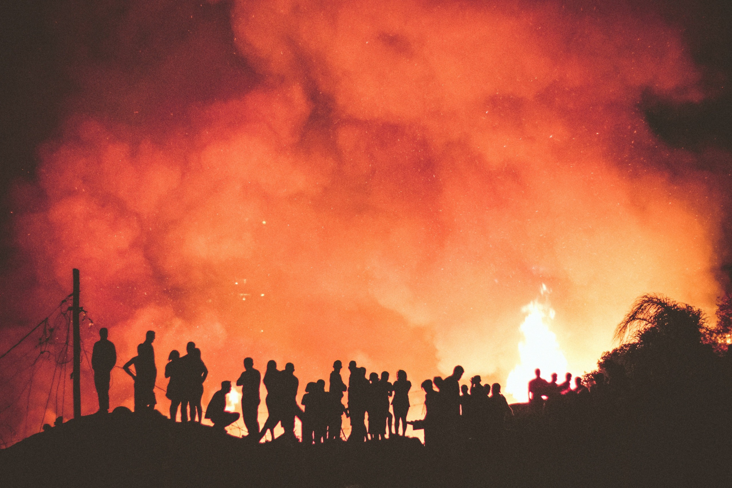 people near fire during night - photo by denys argyriou